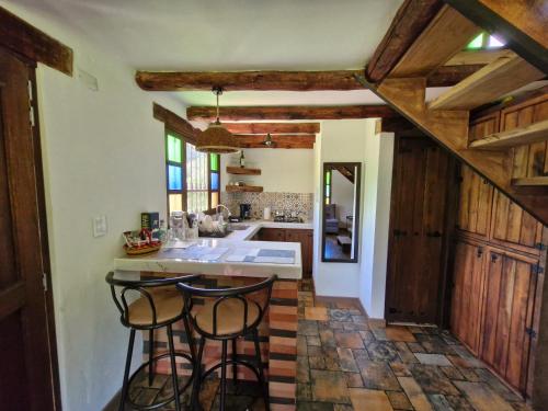 a kitchen with a sink and two bar stools at Hospedaje Resguardo Real in Ráquira