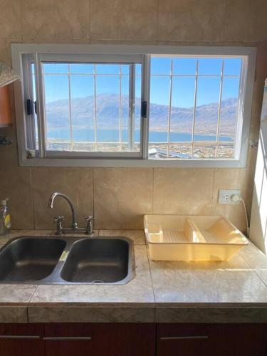eine Küchentheke mit einem Waschbecken und einem Fenster in der Unterkunft Casa en la montaña con gran vista al valle y lago in El Mollar