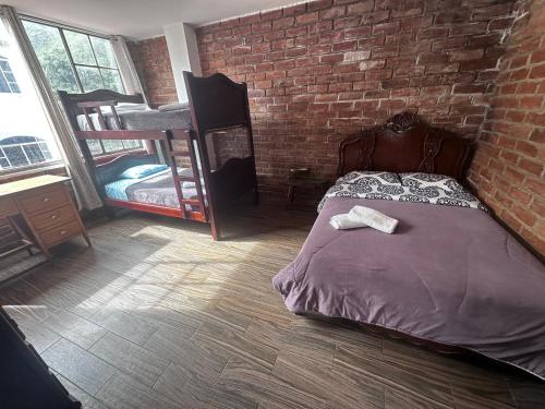 a bedroom with a bed and a brick wall at Baños de agua Santa in Baños