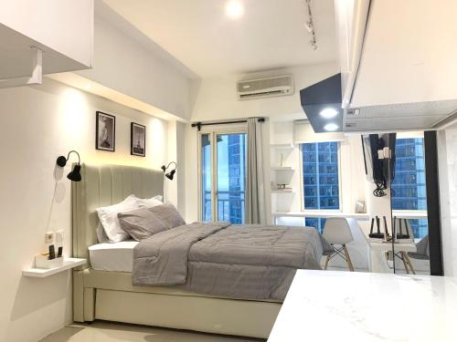 a bedroom with a bed and a desk and some windows at Pakuwon Mall Dovey Apartment in Surabaya