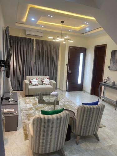 uma sala de estar com um sofá, uma mesa e cadeiras em Majorstone Luxury Apartment em Ibadan