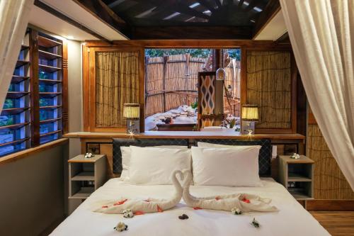 una camera da letto con un letto con due cigni sopra di Barefoot Kuata Island Resort a Kuata