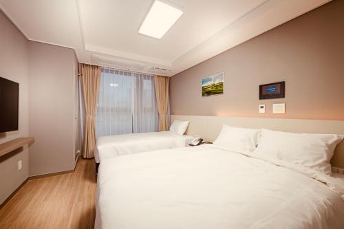 a hotel room with two beds and a television at Sollago Myeongdong Hotel & Residence in Seoul