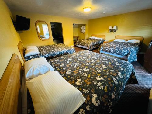 a hotel room with three beds in a room at Mount Whitney Motel in Lone Pine