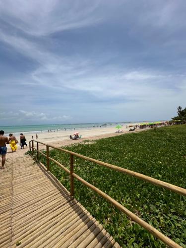 a wooden boardwalk leading to a beach with people at Naluum Milagres in Passo de Camarajibe