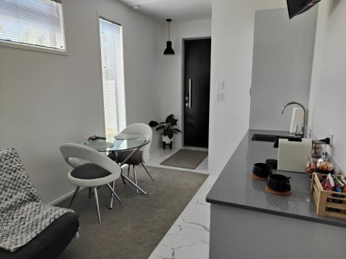 een keuken met witte muren en een tafel en stoelen bij Marina Views in One Tree Point