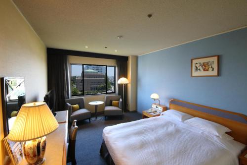 佐賀市にあるホテルニューオータニ佐賀のベッドと窓が備わるホテルルーム