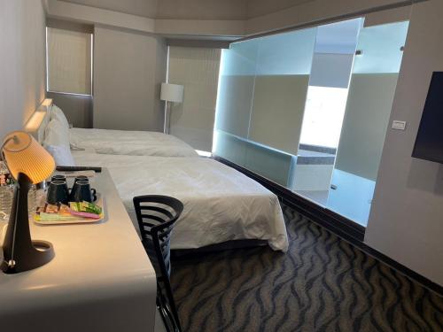 a hotel room with a bed and a desk with a mirror at 藝築文旅-昆明館Artinn Kunming in Taipei