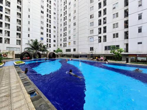 une grande piscine en face de grands bâtiments dans l'établissement Apt Bassura Studio Tower F w/ Pool, Wi-Fi & Netflx, à Jakarta