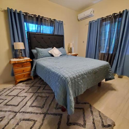 um quarto com uma cama com um edredão azul em Get Away Zone em Montego Bay