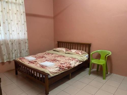 a bedroom with a bed and a green chair at NaVita Homestay in Tamparuli