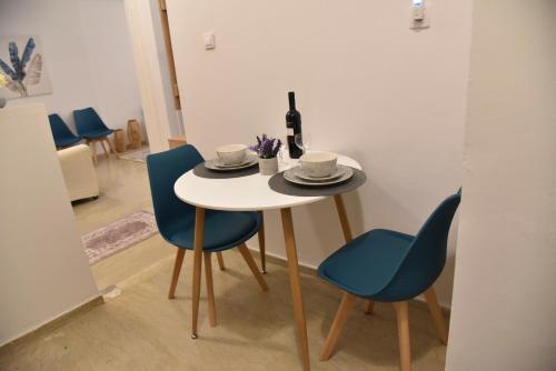 een tafel met twee blauwe stoelen en een fles wijn bij Citrus dream apartment in Athene