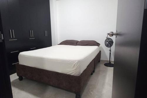 ein Schlafzimmer mit einem Bett mit weißer Bettwäsche und einer Lampe in der Unterkunft Apartamento central y tranquilo in Palmira
