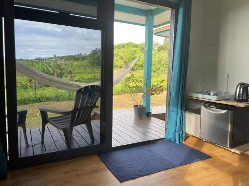 a room with a glass door with a chair on a deck at Bungalow Tiny House Puunui 