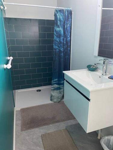 a bathroom with a blue shower curtain and a sink at Bungalow Tiny House Puunui in Katiro