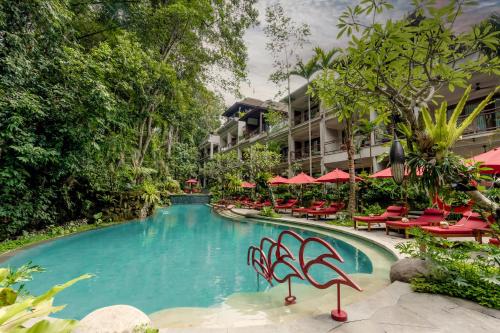 a swimming pool at a resort with chairs and umbrellas at AnandaDara Ubud in Ubud