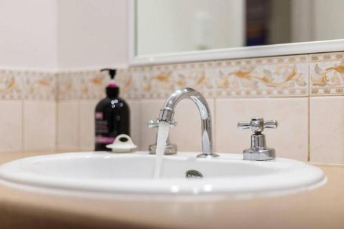 a bathroom sink with a soap dispenser and a bottle of soap at A city oasis - full apartment with balcony in Perth
