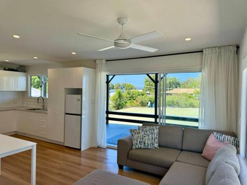 Una sala de estar con un sofá y una cocina. en The Old Artist Residence, Boreen Point Boutique Accomodation, en Cootharaba