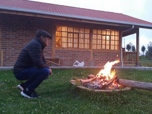 Un uomo accovacciato vicino a un incendio in un giardino di Cabañas Tecla María a Otavalo