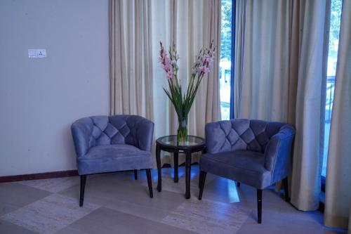 two blue chairs and a table with a vase of flowers at Cedar Lodges Resort and Residences Galiyat in Chhāngla Gali