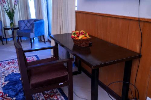 a table with a basket of fruit on it with a chair at Cedar Lodges Resort and Residences Galiyat in Chhāngla Gali