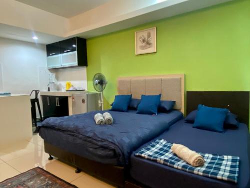 een slaapkamer met een bed met blauwe kussens en een groene muur bij Private Studio Viana Court Service Apartment 2 with private parking in Kota Bharu