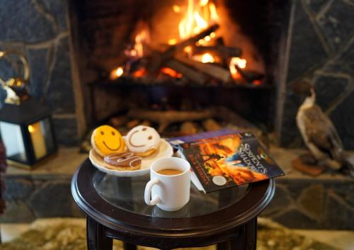 a cup of coffee and a plate of food in front of a fireplace at Cedar Lodges Resort and Residences Galiyat in Chhāngla Gali