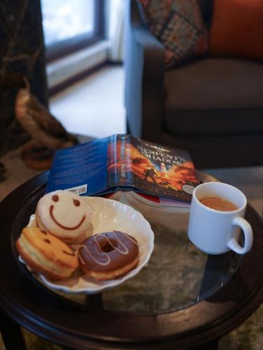 a table with a plate of donuts and a cup of coffee at Cedar Lodges Resort and Residences Galiyat in Chhāngla Gali