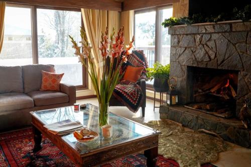 a living room with a fireplace and a vase of flowers at Cedar Lodges Resort and Residences Galiyat in Chhāngla Gali