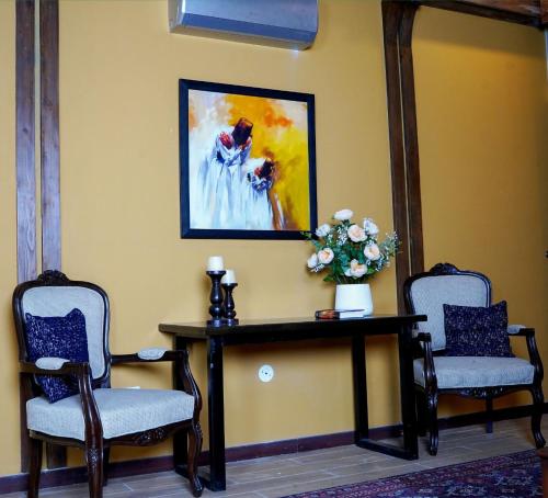 two chairs and a table with a vase of flowers at Cedar Lodges Resort and Residences Galiyat in Chhāngla Gali