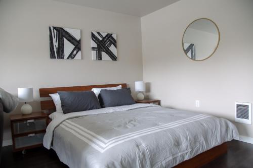 a white bedroom with a large bed and a mirror at Capitol Hill Modern Studio with Free Parking! in Seattle