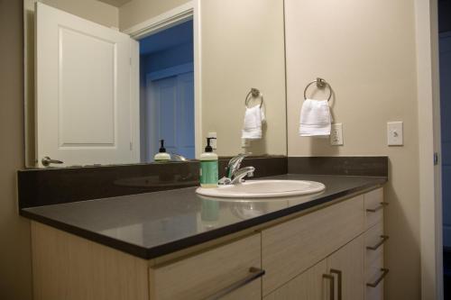 a bathroom with a sink and a large mirror at Capitol Hill Modern Studio with Free Parking! in Seattle