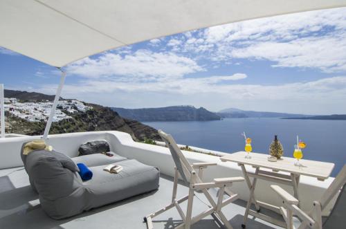 a balcony with a table and chairs and a view of the water at Ambition Suites in Oia