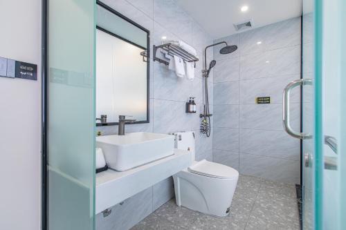 W łazience znajduje się umywalka, toaleta i lustro. w obiekcie Zhuhai Golden Lake Bay Hotel w mieście Zhuhai