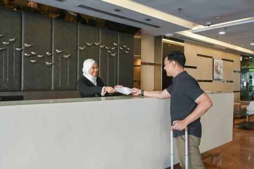 Um homem e uma mulher atrás de um balcão. em Hotel Pudu Plaza Kuala Lumpur em Kuala Lumpur