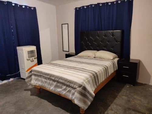 Schlafzimmer mit einem großen Bett und blauen Vorhängen in der Unterkunft Mi casa in Ciudad Juárez