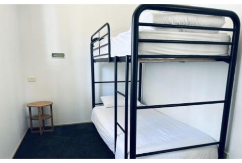 two bunk beds in a room with a stool at Discovery Parks - Narooma Beach in Narooma