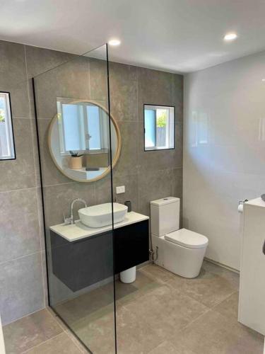 een badkamer met een wastafel, een toilet en een spiegel bij Studio 2 Boreen Point Boutique Accommodation in Cootharaba