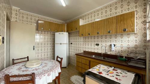 eine Küche mit einem Tisch und einem weißen Kühlschrank in der Unterkunft Desativado in São Vicente