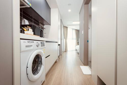 a laundry room with a washing machine and a hallway at Sollago Myeongdong Hotel & Residence in Seoul