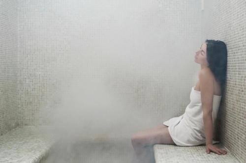 a woman in a white dress sitting on a wall at Hotel Centro Benessere Gardel in Arta Terme