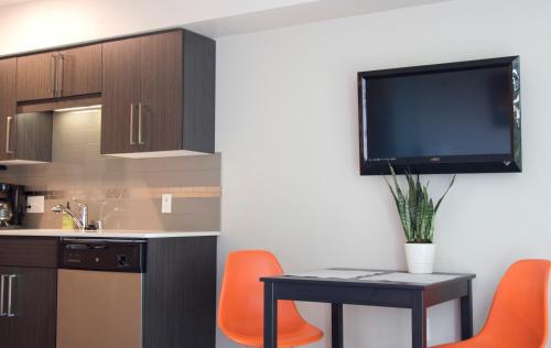 a kitchen with orange chairs and a table with a tv on the wall at Amazing Capitol Hill Apartment with Free Parking! in Seattle