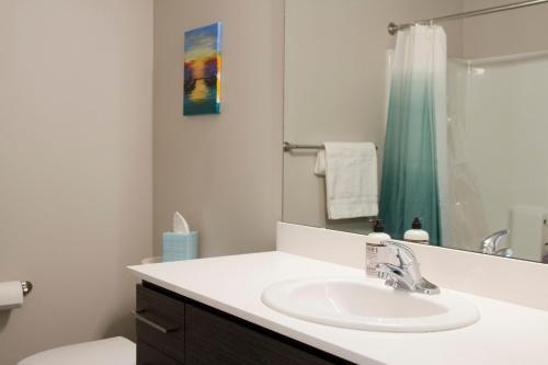 a white bathroom with a sink and a mirror at Amazing Capitol Hill Apartment with Free Parking! in Seattle