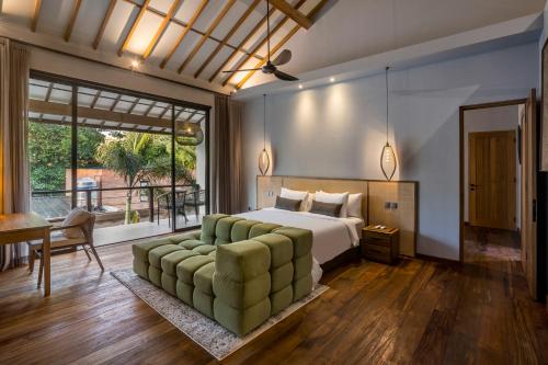 a bedroom with a bed and a couch and a table at Villa Sessun by Alfred in Bali in Canggu