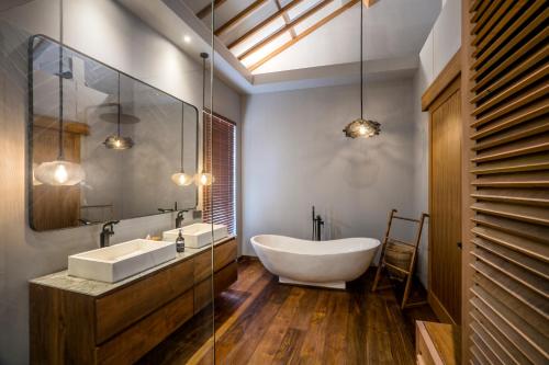 a bathroom with a tub and a sink and a mirror at Villa Sessun by Alfred in Bali in Canggu