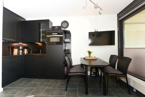 a kitchen with black cabinets and a table at Haus Bi de Wyk D1B in Südstrand