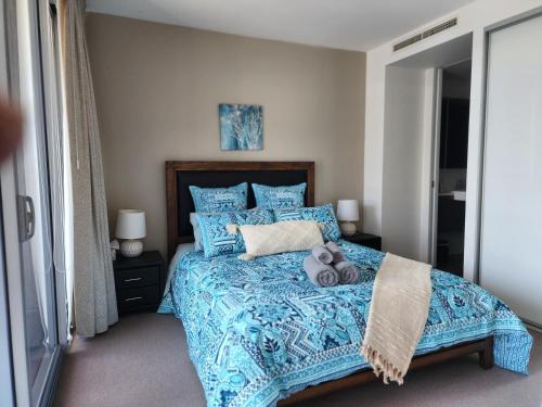 Un dormitorio con una cama azul con un osito de peluche. en Lakefront Views on the foreshore en Kingston 