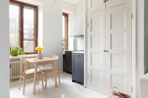 a kitchen with a small table and a white door at Charming suite with garden views steps from metro in Helsinki