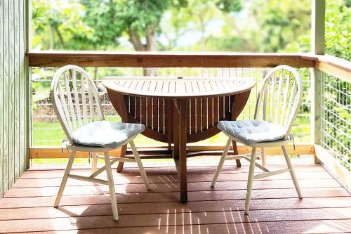 ein Holztisch und zwei Stühle auf einer Veranda in der Unterkunft PonoMana Oasis's - Zen Cottage in Captain Cook