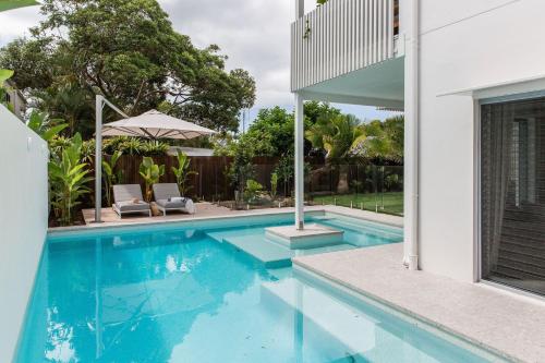 a swimming pool with two chairs and an umbrella at AL Sole - 4 Bedrooms - Pool - Location in Sunshine Beach